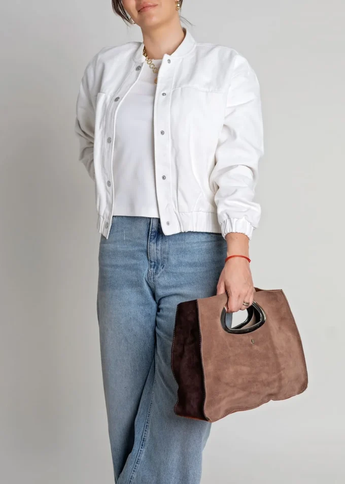 Modelka trzymająca w ręku torebkę Bellini w brązach – stylizacja casual z białą kurtką i jeansami