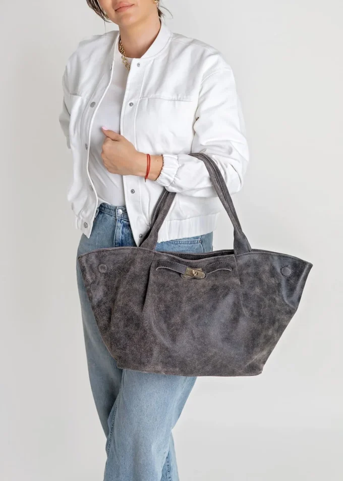 Kobieta w białej kurtce i jeansach trzymająca shopperkę Mila z naturalnego zamszu